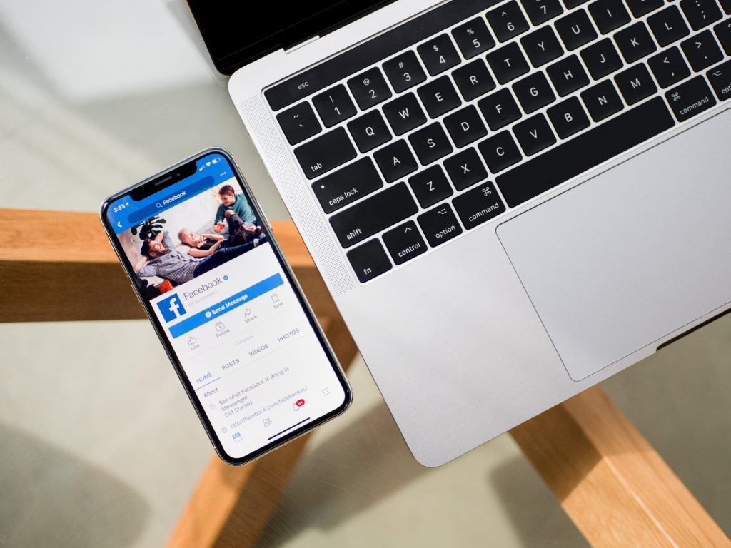 meer social media volgers salon, foto van telefoon met facebookprofiel naast macbook