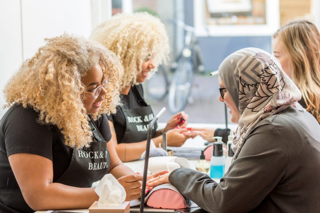 foto van salonmedewerkers die de nagels van klanten doen, voor artikel over stoelverhuur