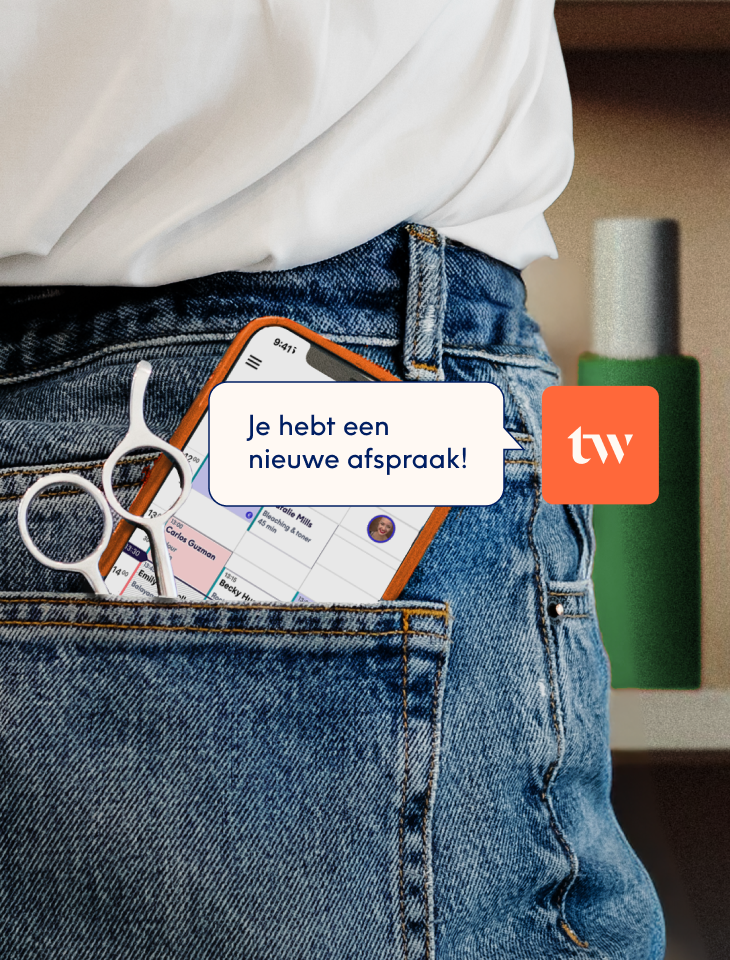 Een smartphone en een kappersschaar in de achterzak van een spijkerbroek, met op het scherm de boekingsagenda van de Treatwell-app en een melding "Je hebt een nieuwe afspraak".